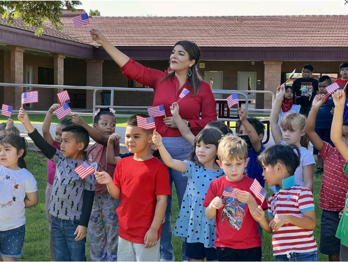 Patriots Day Assembly teacher and students waving flags